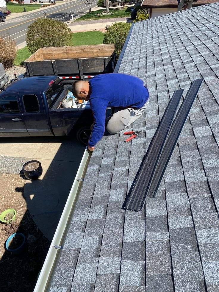 A Mansfield Services technician installing gutter guards on a Vermont home